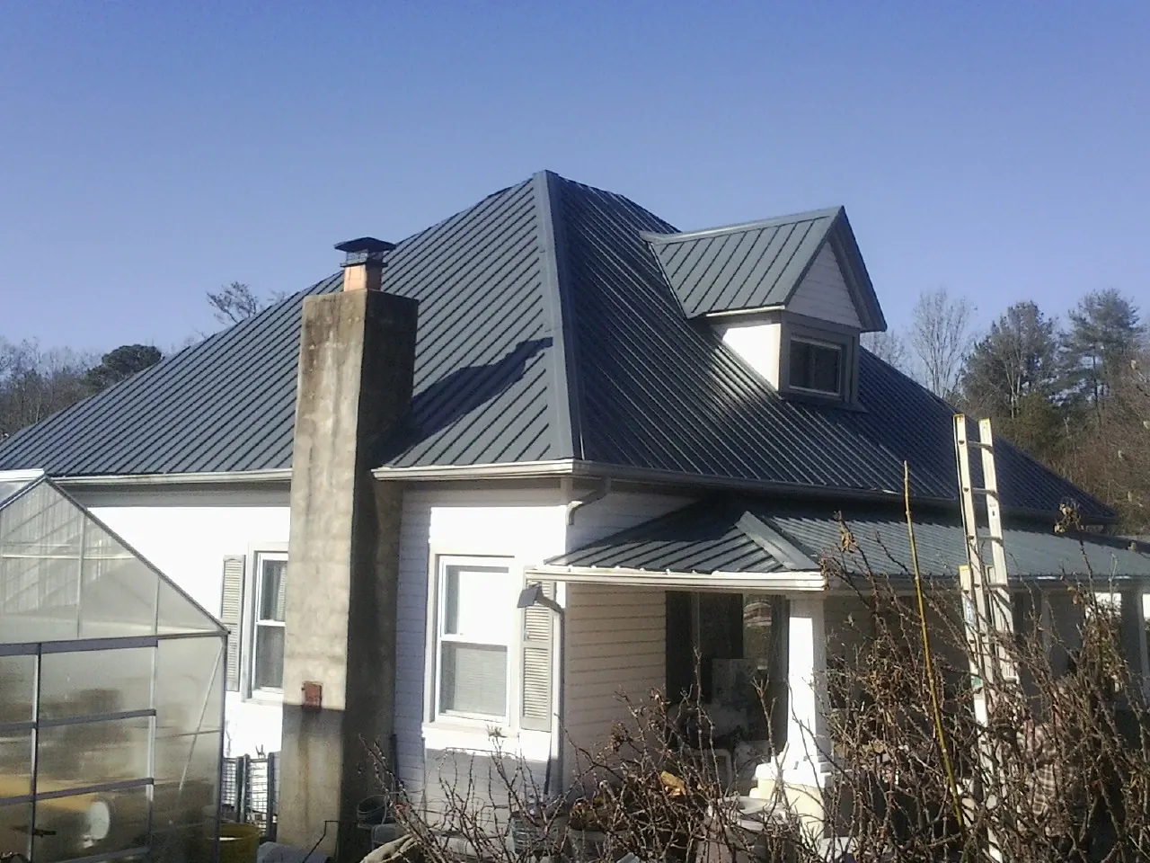 Dark blue standing seam metal roof on a white farmhouse with dormer — Slate & Tile Roof Repair by Roofing Brothers in Transfer