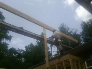 Carpenter setting a ridge beam over a new addition frame — Ice Dam Removal by Roofing Brothers in Transfer