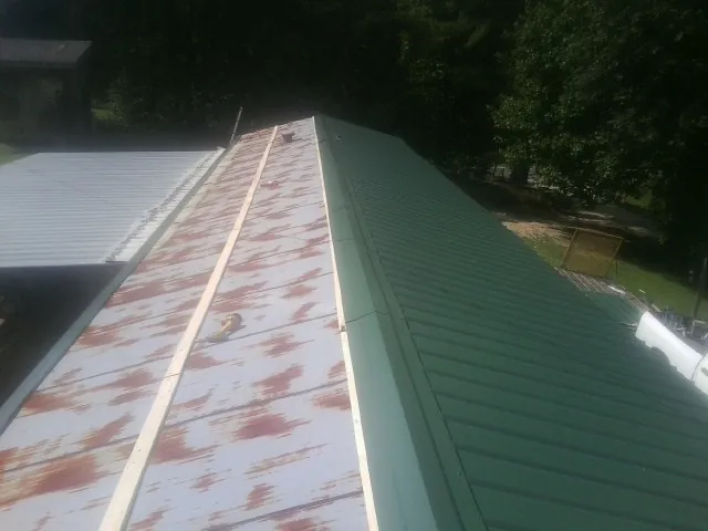 Old rusted panels beside newly installed green metal roofing — Wind Damage Roof Repair by Roofing Brothers in Transfer