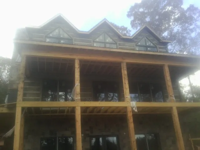 Dormers and porch framing on a large log home under construction — Roof Coating work by our crew in Transfer