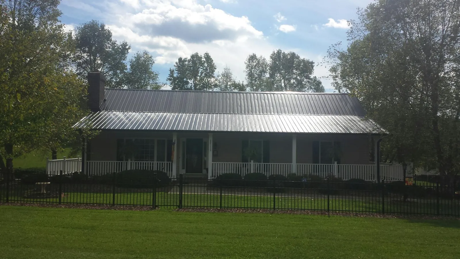 Gray metal roof on a brick ranch with a full width front porch — Gutter Guard Installation work by our crew in Transfer