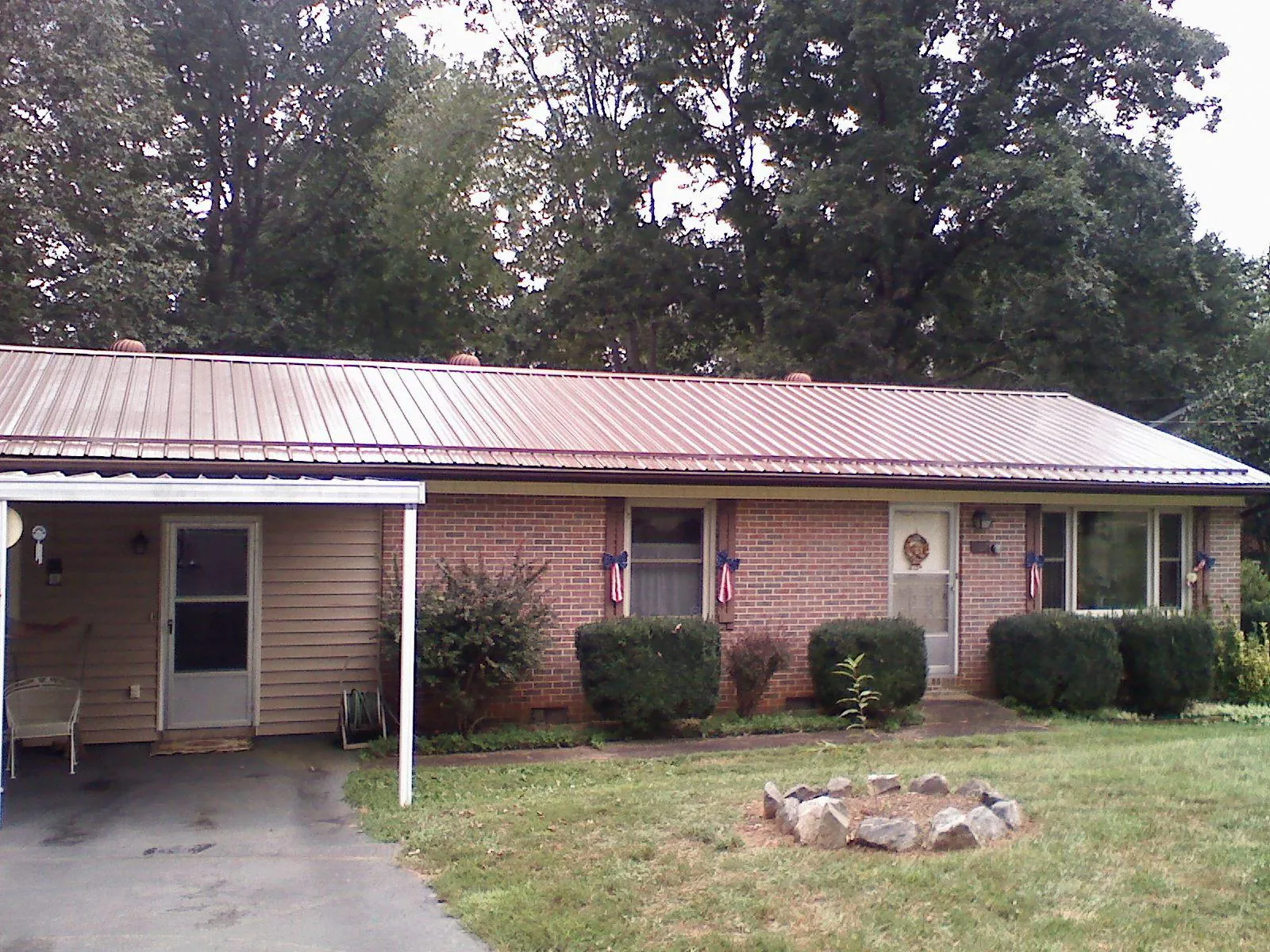 Bronze metal roof and carport on a brick ranch home — Roof Repair work by our crew in Transfer
